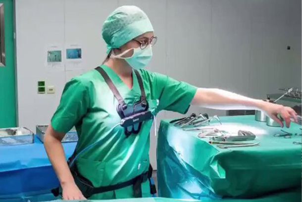 Exoskelett getragen von einer Pflegerin über der Arbeitskleidung im OP-Saal